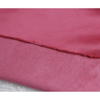 Gros plan sur un tissu satiné rose à bord brut, idéal pour être associé à Suédine unie embossée au mètre de Longan Craft France, un daim synthétique de qualité supérieure parfait pour les projets textiles créatifs.