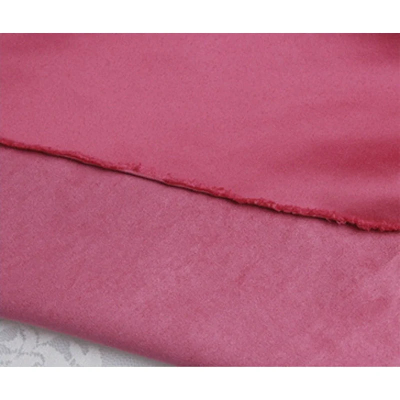 Gros plan sur un tissu satiné rose à bord brut, idéal pour être associé à Suédine unie embossée au mètre de Longan Craft France, un daim synthétique de qualité supérieure parfait pour les projets textiles créatifs.