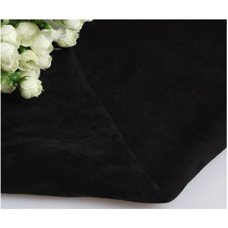 Un bouquet de fleurs blanches repose sur un morceau de Longan Craft France Suédine unie embossée au mètre, un tissu en daim synthétique de haute qualité pour les vêtements, couvrant la majeure partie de l'image avec sa surface lisse et douce.