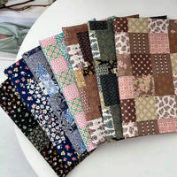 Huit pièces de Longan Craft France Linon de coton imprimé floral ethnique au mètre, présentant des motifs de patchwork bleu, rose, marron, vert et crème, sont disposées en éventail sur une table ronde blanche.