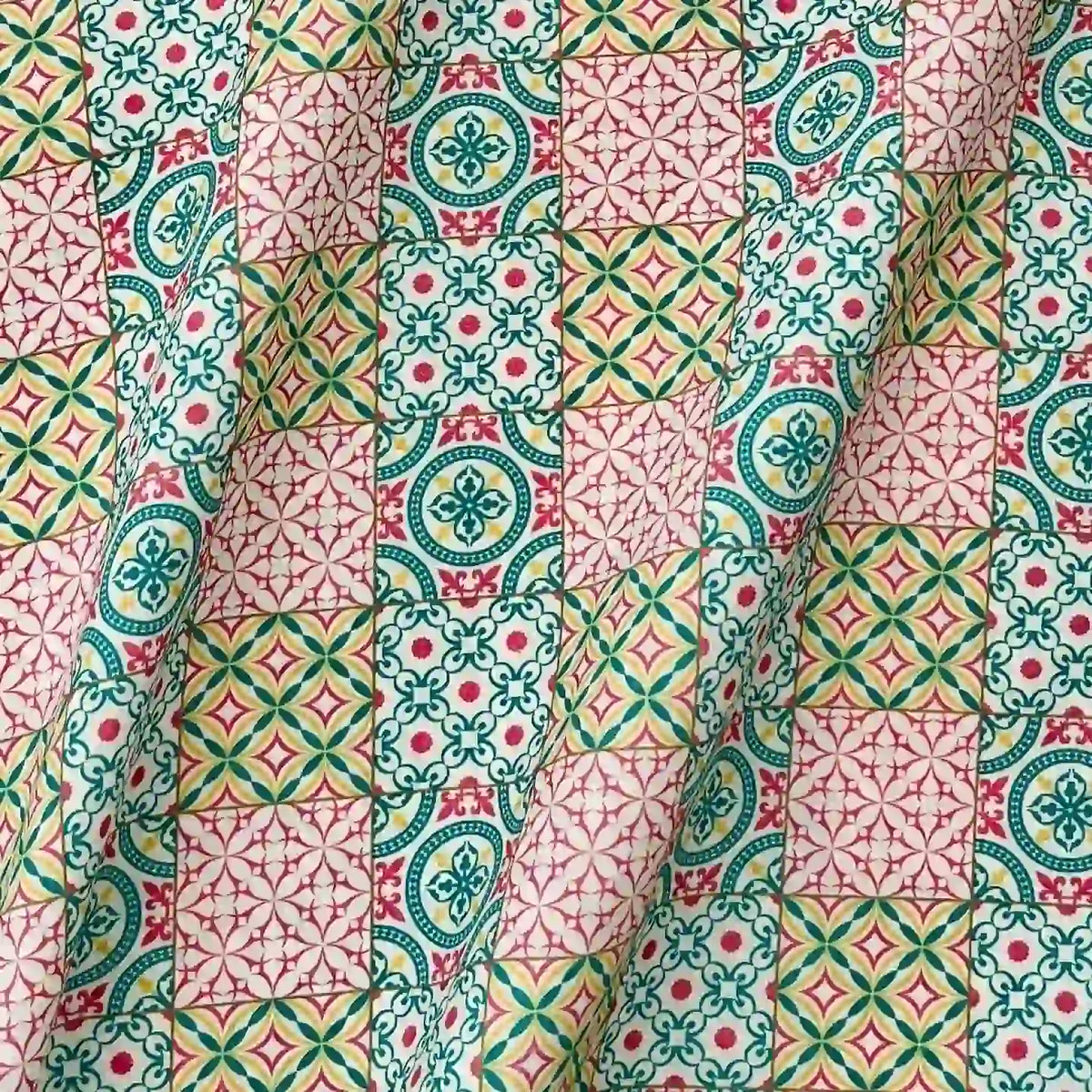 Gros plan sur le Linon de coton imprimé floral ethnique au mètre de Longan Craft France, montrant son motif géométrique avec des formes florales et étoilées colorées sur une surface de coton pliée et froissée - idéal pour les vêtements de style vintage.