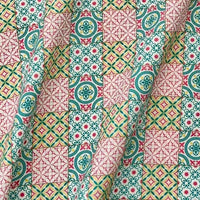 Gros plan sur le Linon de coton imprimé floral ethnique au mètre de Longan Craft France, montrant son motif géométrique avec des formes florales et étoilées colorées sur une surface de coton pliée et froissée - idéal pour les vêtements de style vintage.