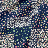 Linon de coton imprimé floral ethnique au mètre par Longan Craft France : tissu linon vintage avec motif patchwork de petites fleurs blanches, jaunes, roses et vertes sur fond bleu foncé, surface légèrement froissée. Idéal pour robes et vêtements.
