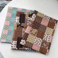 Trois carnets aux couvertures inspirées du Linon de coton imprimé floral ethnique de Longan Craft France, présentant des carrés de patchwork marron et rose ainsi qu'un motif géométrique sarcelle et rose, sont présentés sur une surface blanche.