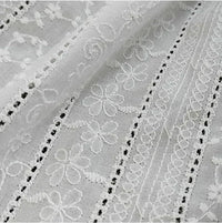 Gros plan sur le Tissu en coton brodé floral au mètre de Longan Craft France : un tissu denim ajouré, léger et semi-transparent, avec des rangées de fleurs et de motifs géométriques brodés, détaillés avec de l'œillet et de la dentelle - idéal pour les robes et les chemisiers.