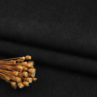 Un faisceau de fleurs brunes séchées repose sur le tissu Longan Craft France velours côtelé uni plié, dont la texture finement côtelée est idéale pour les canapés, les vêtements et les pantalons, et qui est vendu au mètre.