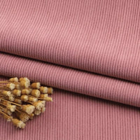 Gros plan sur le Tissu velours côtelé à fines côtes au mètre de Longan Craft France, soigneusement plié, avec un petit bouquet de fleurs beiges séchées posé sur le tissu - idéal pour les canapés, les vêtements et les pantalons.
