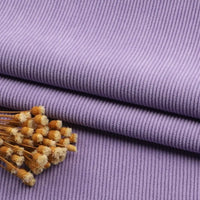 Un morceau de Tissu velours côtelé à fines côtes au mètre de Longan Craft France est plié, sur lequel repose un petit bouquet de fleurs séchées jaunes et blanches.