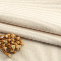 Gros plan sur un pli en tissu velours côtelé à fines côtes au mètre de Longan Craft France, sur lequel est posé un petit bouquet de fleurs séchées de couleur beige. Idéal pour les canapés, les vêtements et les pantalons.