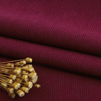 Gros plan sur le tissu velours côtelé à fines côtes au mètre de Longan Craft France en marron, soigneusement plié avec des fleurs jaunes séchées sur le dessus, mettant en valeur la texture élégante - idéale pour les canapés, les vêtements et les pantalons.