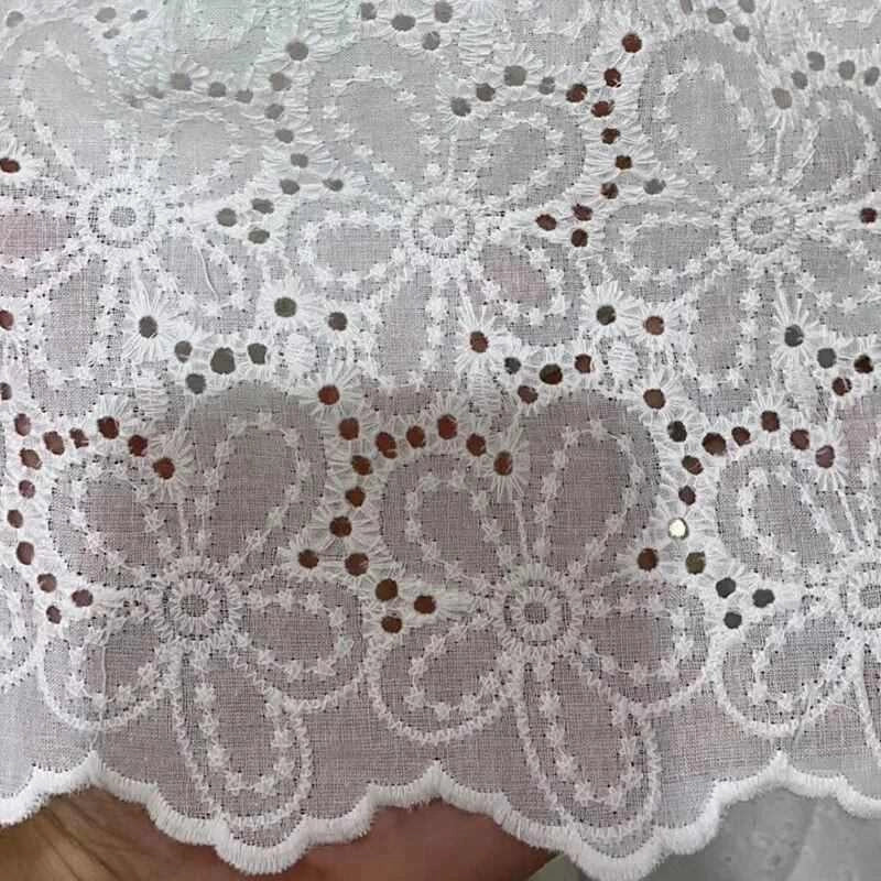 Gros plan sur le tissu œillet brodé floral au mètre de Longan Craft France, un tissu de coton léger avec de grands motifs floraux, de petits œillets et un bord festonné pour un aspect délicat et aéré.