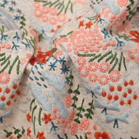 Gros plan sur le Tissu brodé floral au mètre de Longan Craft France : tissu en coton-linen avec des broderies florales détaillées roses, orange, vertes et bleues - idéal pour la décoration intérieure ou la couture de vêtements.