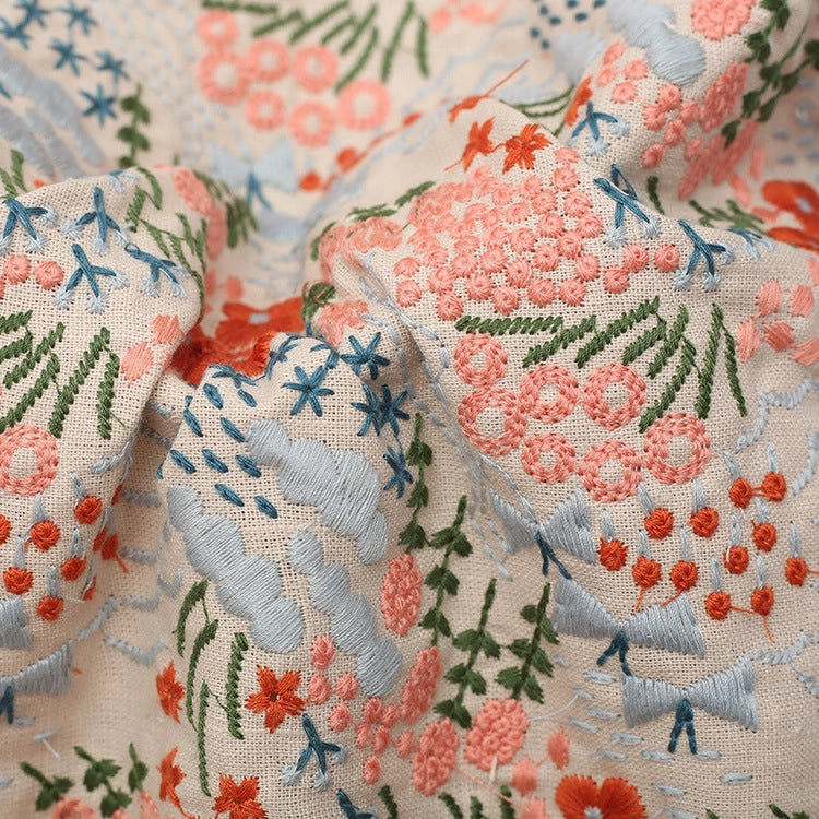 Gros plan sur le Tissu brodé floral au mètre de Longan Craft France : tissu en coton-linen avec des broderies florales détaillées roses, orange, vertes et bleues - idéal pour la décoration intérieure ou la couture de vêtements.