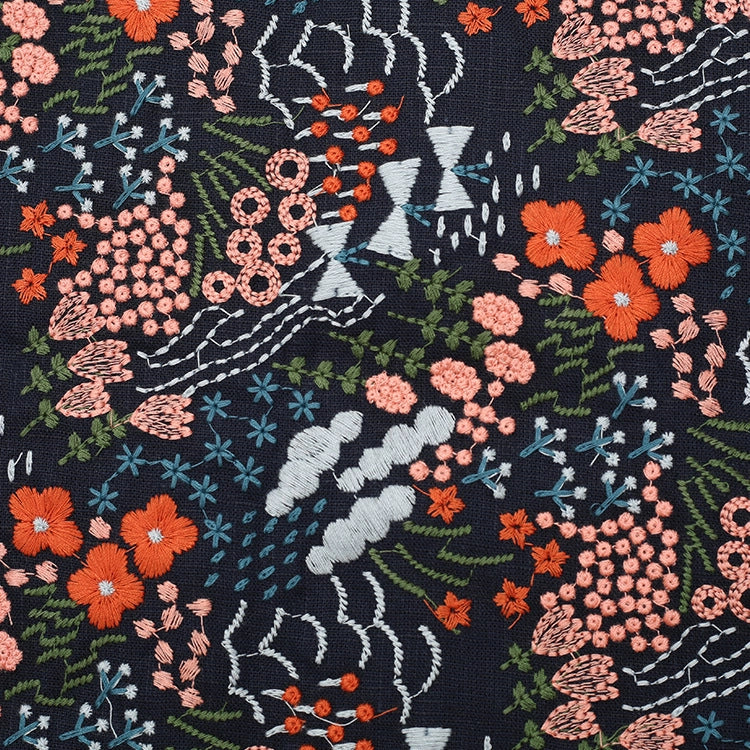 Le tissu brodé floral au mètre, en coton-lin, de Longan Craft France offre un motif de fleurs orange, roses et bleues avec feuilles vertes sur fond sombre et accents géométriques blancs, idéal pour décoration intérieure ou couture.