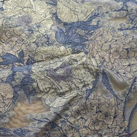 Un gros plan du tissu organza brodé floral au mètre de Longan Craft France montre une broderie bleue et crème détaillée, donnant au tissu transparent un aspect texturé, idéal pour les décors élégants ou la confection de vêtements.