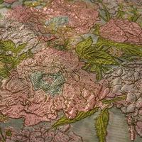 Gros plan sur une broderie florale rose et verte sur Tissu organza brodé floral au mètre par Longan Craft France, montrant de grandes fleurs et feuilles détaillées sur un tissu brillant et transparent idéal pour les robes.