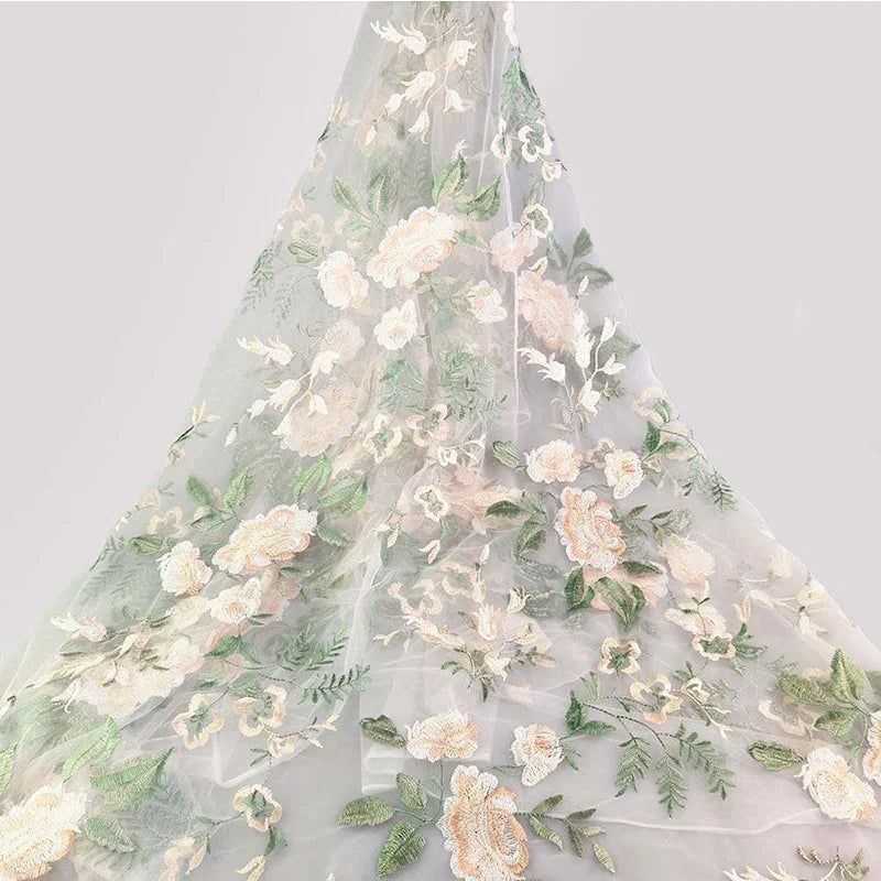 Tulle brodé floral au mètre de Longan Craft France, en blanc avec motifs floraux brodés rose pâle, blanc et vert, idéal pour couture de robe de mariée ou créations élégantes en tissu polyester délicat.
