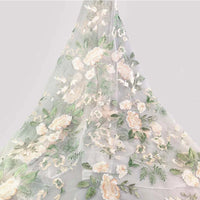 Tulle brodé floral au mètre de Longan Craft France, en blanc avec motifs floraux brodés rose pâle, blanc et vert, idéal pour couture de robe de mariée ou créations élégantes en tissu polyester délicat.
