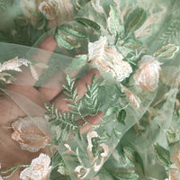 Tulle brodé floral au mètre de Longan Craft France, un tissu polyester vert transparent avec des broderies de fleurs blanches et beiges - parfait pour la couture de robes de mariée.
