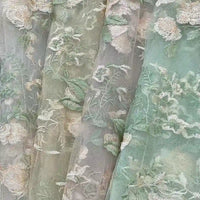Le Tulle brodé floral au mètre de Longan Craft France - des panneaux transparents avec des broderies vertes, crème et beiges - apporte un style élégant à la couture nuptiale ou à tout autre espace.