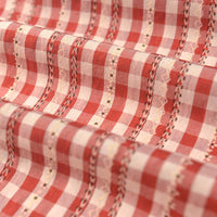 Gros plan sur le Tissu popeline fleurie et vichy au mètre de Longan Craft France, une élégante popeline de coton-polyester à carreaux vichy rouges et blancs, avec des lignes décoratives surpiquées, de petits motifs, des plis doux et une finition subtilement texturée.