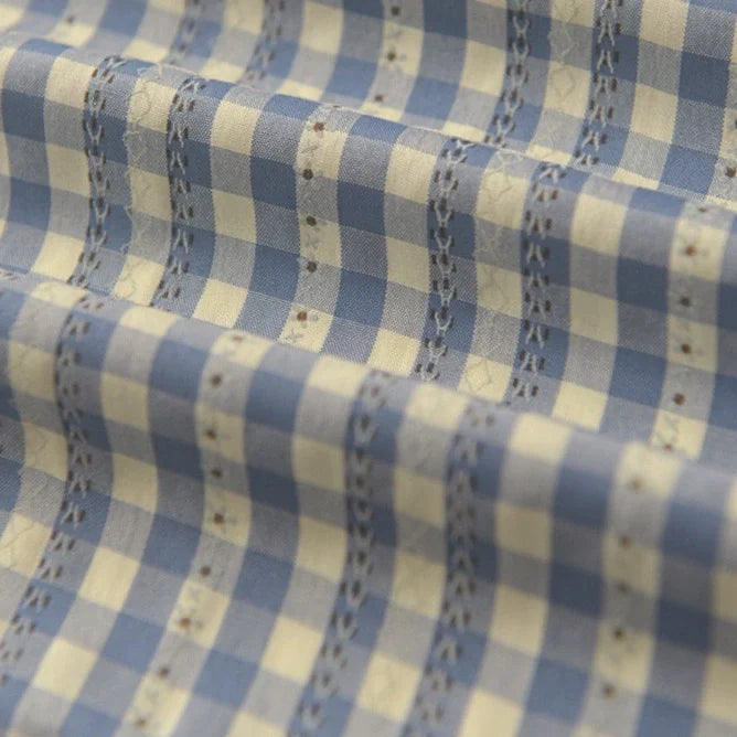 Gros plan sur l'élégant tissu popeline fleurie et vichy au mètre de Longan Craft France, à carreaux bleus et blancs avec surpiqûres décoratives, en coton polyester - parfait pour des vêtements féminins élégants.