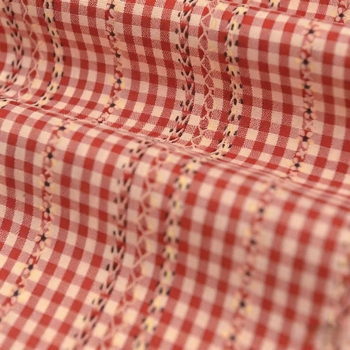 Gros plan sur le Tissu popeline fleurie et vichy au mètre de Longan Craft France, une élégante popeline de coton-polyester à carreaux vichy rouges et blancs, broderie florale et géométrique, légèrement froncée pour une allure féminine.