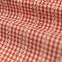 Gros plan sur le Tissu popeline fleurie et vichy au mètre de Longan Craft France, une élégante popeline de coton-polyester à carreaux vichy rouges et blancs, broderie florale et géométrique, légèrement froncée pour une allure féminine.