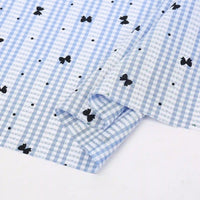 A light blue and white Longan Craft France tissu pour patchwork vichy au mètre, en polyester à motif botanique, partiellement plié pour révéler son motif charmant et sa texture confortable idéale pour vêtements décontractés.