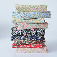 Une pile de tissus colorés en linon et voile de coton imprimé de Longan Craft France, parfaits pour les vêtements et les doublures, disposés sur un fond clair uni.