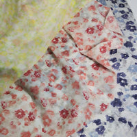 Trois pièces de Longan Craft France Tissu mousseline de soie à imprimé floral au mètre sont disposées : une avec des fleurs jaunes, une avec des fleurs rouges et une avec des fleurs bleues sur fond blanc. Il s'agit d'un tissu léger en soie et coton destiné à la confection de vêtements.