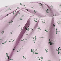 Découvrez notre tissu dobby coton doux Longan Craft France, imprimé au mètre avec un motif floral vert et blanc sur fond rose clair, idéal pour vêtements.