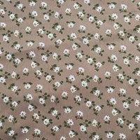 Le Tissu peau de pêche imprimé floral au mètre de Longan Craft France est une microfibre polyester marron, ornée de petites fleurs blanches et feuilles vertes, idéale pour la couture ou tout projet floral grâce à sa texture confortable.