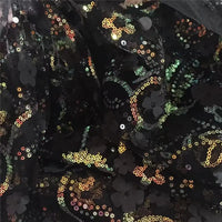 Gros plan sur le "Tissu sequin floral au mètre" de Longan Craft France : résille noire décorée de motifs floraux pailletés dorés, verts et irisés pour un effet brillant et texturé - parfait pour des accessoires de robe étincelants.
