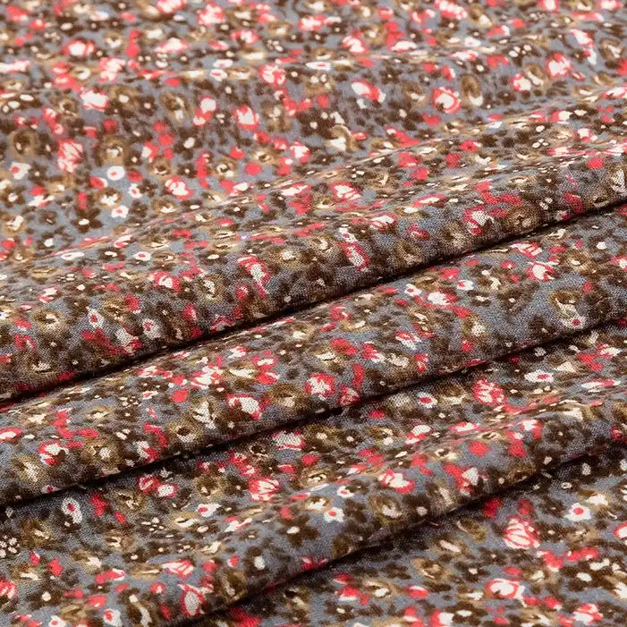 Gros plan sur le tissu en jersey coton imprimé fleurs et animaux de Longan Craft France, montrant des grappes denses de petites fleurs brunes, rouges, blanches et grises - idéal pour créer des robes et des vêtements uniques avec ce jersey au mètre 100 % coton.