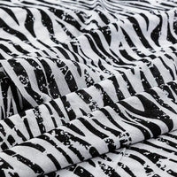 Un gros plan de Tissu en jersey coton imprimé fleurs et animaux de Longan Craft France montre le tissu doux 100% coton jersey plié librement, mettant en évidence son imprimé floral et animalier vibrant, idéal pour les robes et les vêtements.