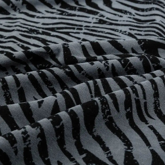 Gros plan sur le tissu jersey 100 % coton de Longan Craft France, à l'imprimé floral et animalier, qui met en valeur sa texture douce et ses plis - idéal pour les robes et les vêtements.