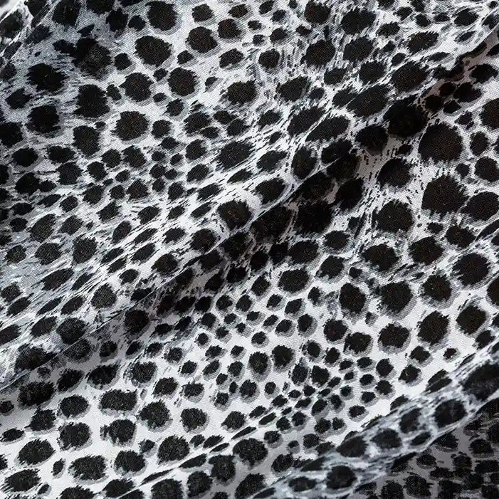 Gros plan sur le tissu en jersey 100 % coton de Longan Craft France, imprimé de motifs floraux et animaliers, parfait pour les robes et les vêtements. Le tissu en jersey coton est légèrement drapé.