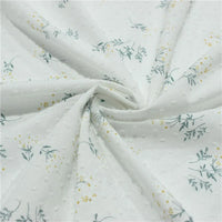 Tissu plumetis fleuri au mètre de Longan Craft France : tissu blanc avec texture à pois, imprimé de petites feuilles vertes et motifs fleuris jaunes, disponible en spirale.
