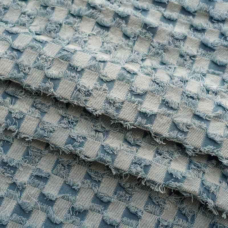 Gros plan sur le tissu denim à franges au mètre de Longan Craft France : un tissu en jean effiloché bleu et gris avec un motif en damier texturé, des bords effilochés et un design en couches - idéal pour les projets de couture décoratifs.