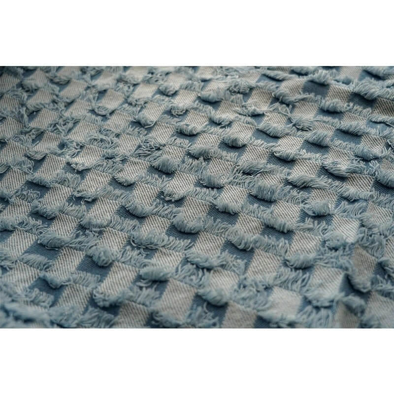 Gros plan sur le "Tissu denim à franges au mètre" de Longan Craft France, une toile de jean décorative et texturée avec des carrés doux en relief et des bords effilochés dans un bleu sourd, parfaite pour des projets de couture polyvalents.