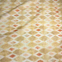 Le tissu en ramie à imprimé géométrique de Longan Craft France, vendu au mètre, présente des tons beige, crème, marron clair et de discrets losanges orange. Sa surface légèrement froissée convient aux robes d'été et créations couture.