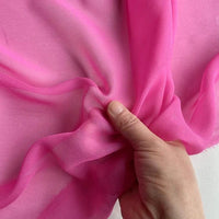 Une main fronce la Georgette de soie au mètre de Longan Craft France, un tissu de crêpe de soie léger et translucide (100 % soie de mûrier, 8 mamans), parfait pour des drapés fluides.