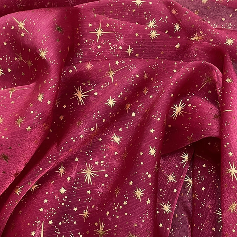 Découvrez le tissu organza étoilé au mètre de Longan Craft France : un organza imprimé bordeaux décoré d'étoiles et de points dorés, légèrement transparent et souple, idéal pour robes de mariée et costumes de mariage.