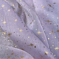 Gros plan sur le Tissu organza étoilé au mètre de Longan Craft France : organza transparent de couleur lavande avec des étoiles et des paillettes dorées. Léger, légèrement drapé, il est parfait pour les robes de mariée et les costumes.