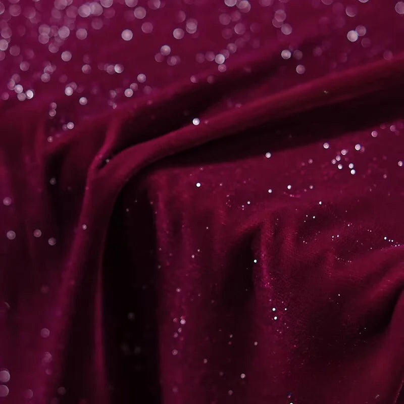 Gros plan sur le Tissu velours pailleté au mètre de Longan Craft France : un doux velours de polyester bordeaux parsemé de paillettes argentées, parfait pour les robes de soirée DIY et les décors de couture. Texture scintillante et luxueuse montrée en détail.