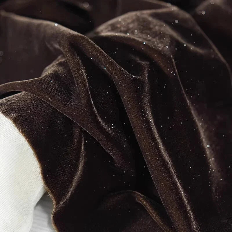 Gros plan sur le tissu velours pailleté au mètre de Longan Craft France, un doux velours polyester argenté aux accents étincelants et aux plis délicats ; une touche de tissu blanc sur le bord - idéal pour une décoration de couture ou de robe de soirée DIY.