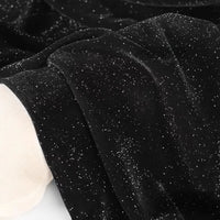 Gros plan sur le tissu velours pailleté au mètre de Longan Craft France : velours polyester doux argenté avec une finition étincelante, drapé en plis souples. Un bord blanc apparaît dans le coin - idéal pour la décoration, les robes de soirée et la couture DIY.