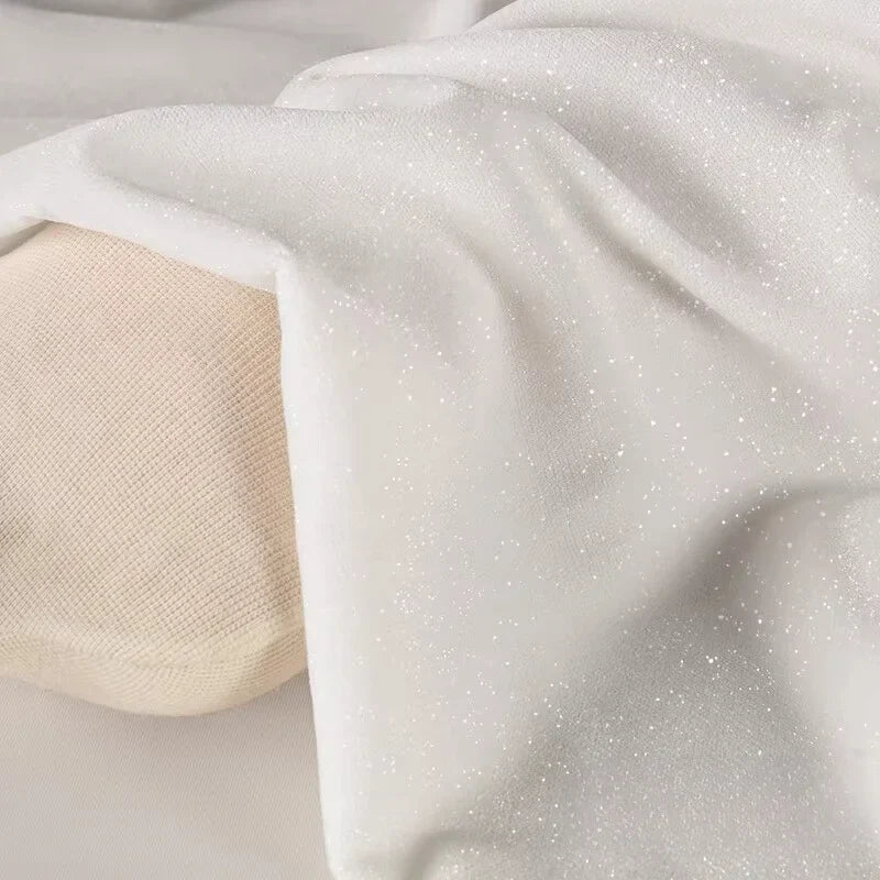 Gros plan sur le doux tissu velours pailleté argenté de Longan Craft France, drapé sur une surface beige, idéal pour la décoration ou DIY robes de soirée.