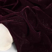 Gros plan sur le tissu velours pailleté au mètre de Longan Craft France, un tissu velours pailleté en polyester doux et argenté, drapé sur un cylindre recouvert de blanc - parfait pour les robes de soirée DIY et les projets de couture.